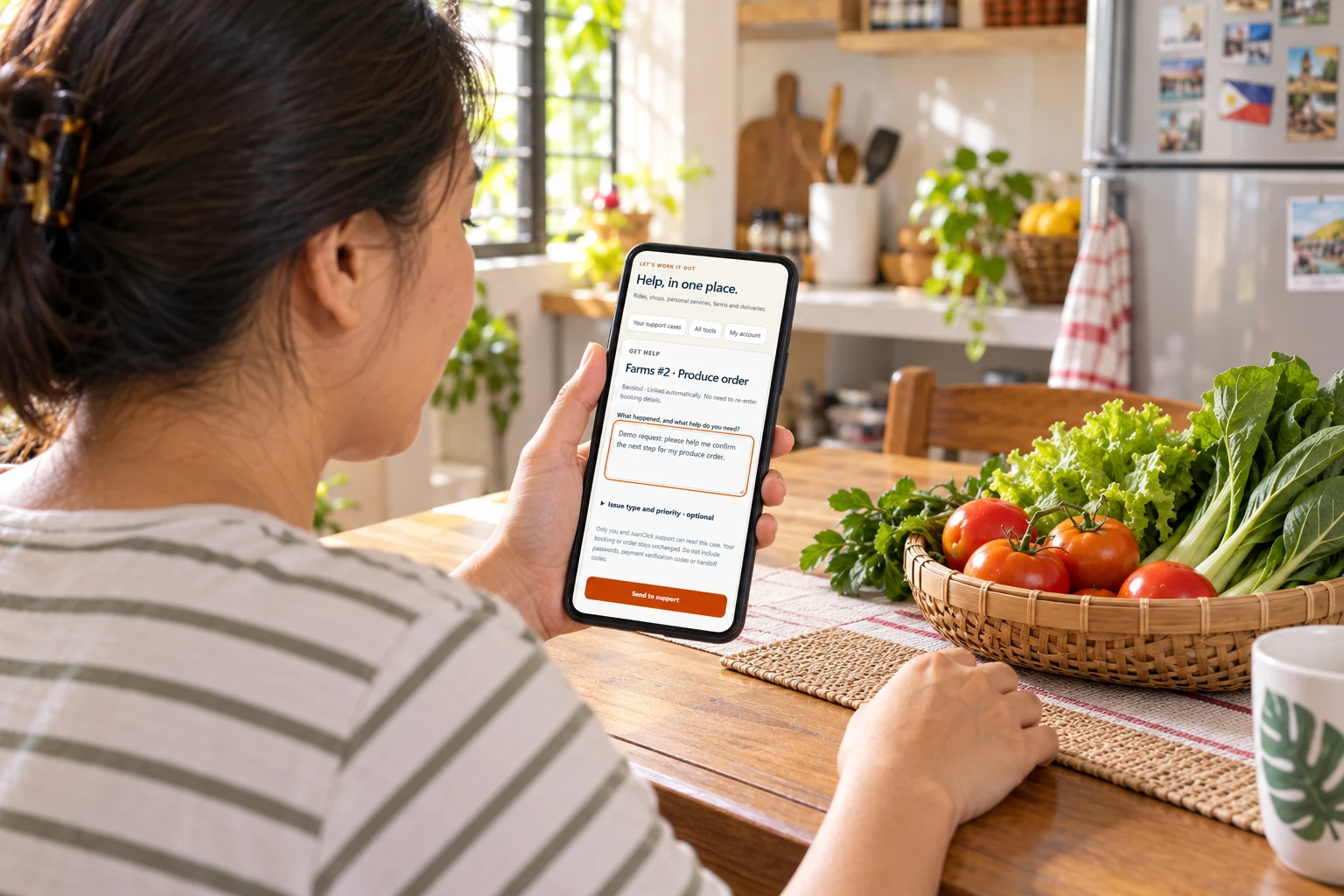 AI-generated fictional customer using a naturally proportioned smartphone to request JuanClick support beside fresh produce; actual app screen used as reference