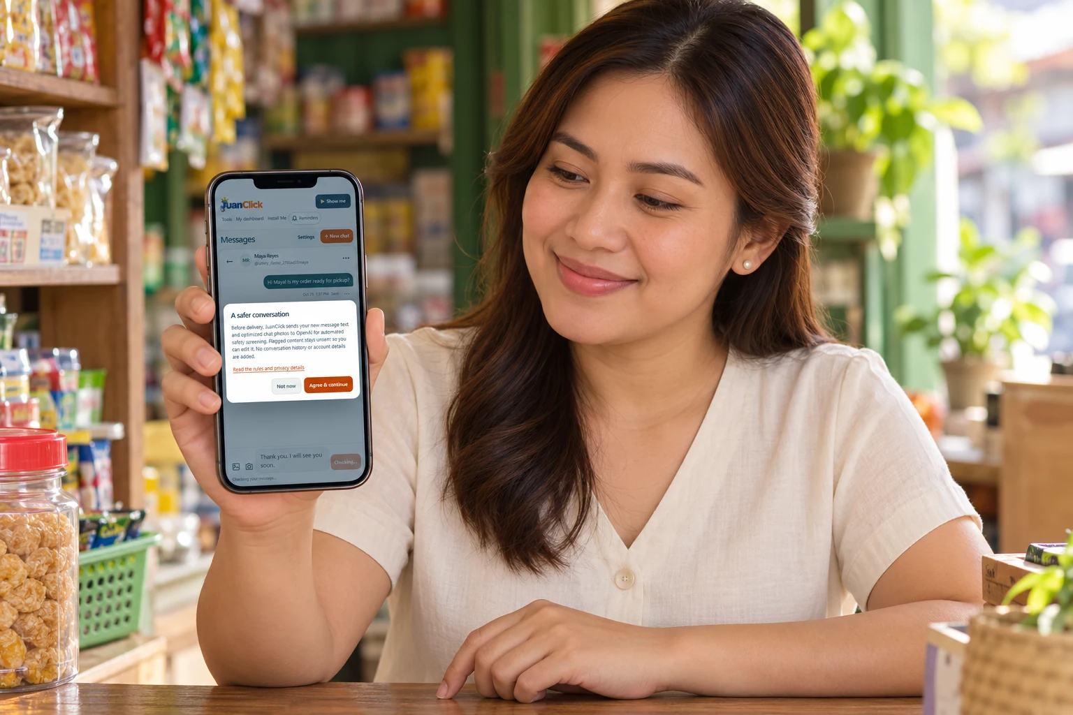 Fictional Filipino shopkeeper holding a normal-sized phone showing the actual JuanClick safety-consent screen